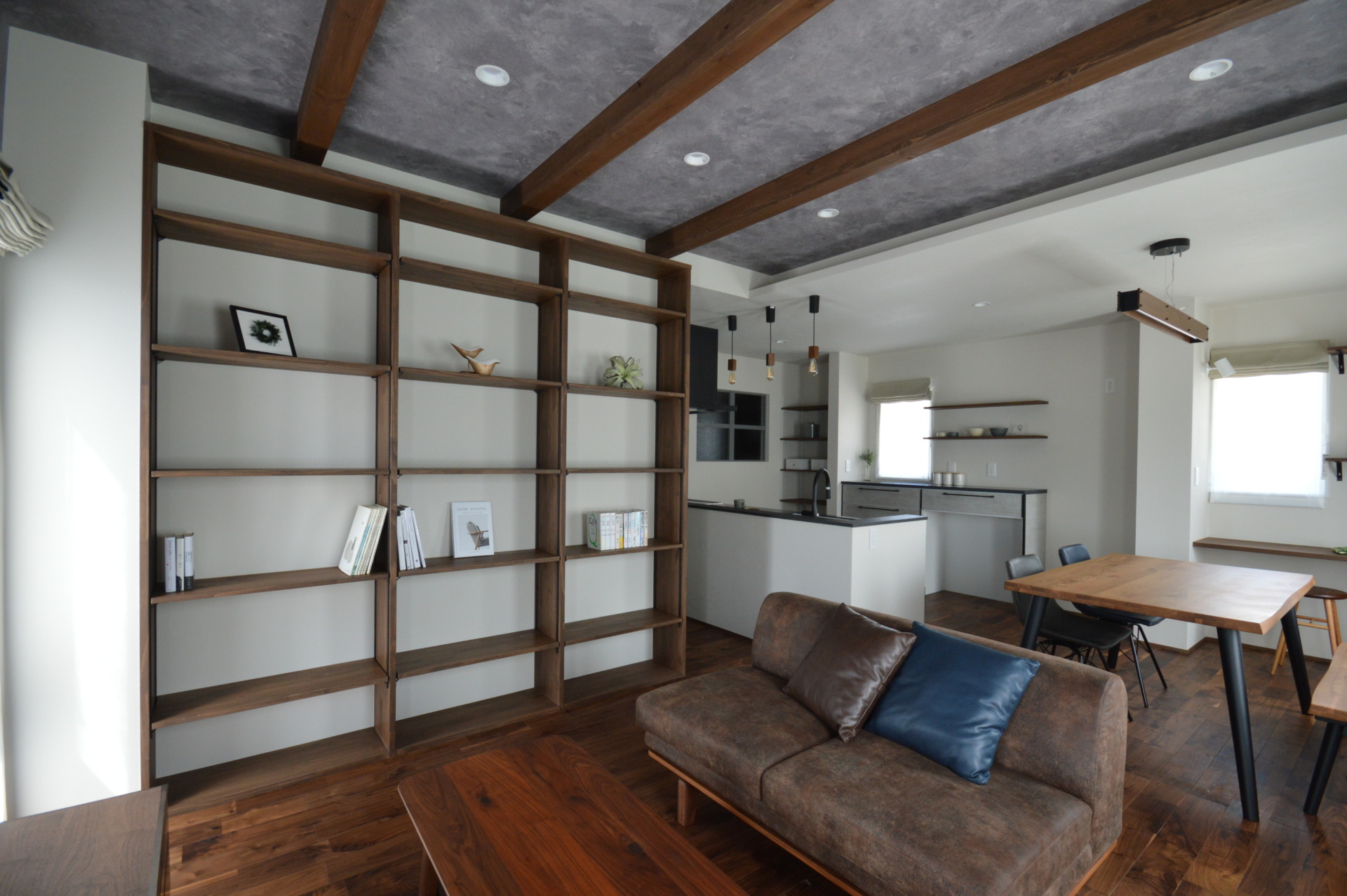 造作大型本棚のあるリビング｜天井梁とモルタル調壁のある注文住宅